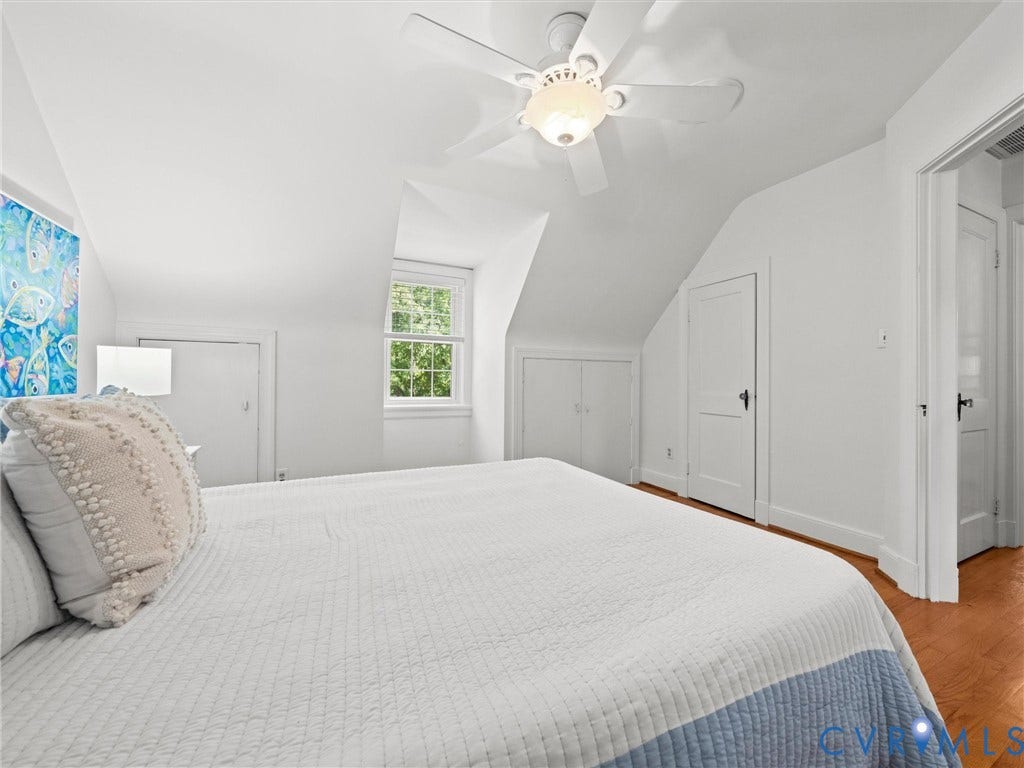 Angled ceilings with clean white finishes, hardwood-finish flooring, and a ceiling fan with integrated lighting