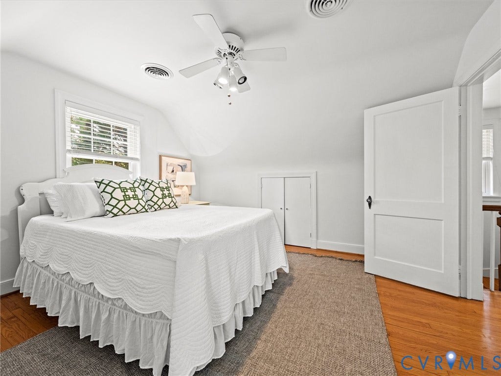 Hardwood flooring with a white paneled door, built-in closet, and ceiling fan