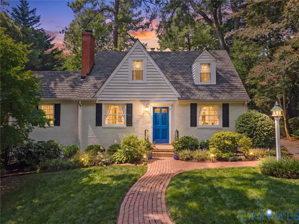 Brick exterior with a prominent chimney, dormer windows, and a blue entry door