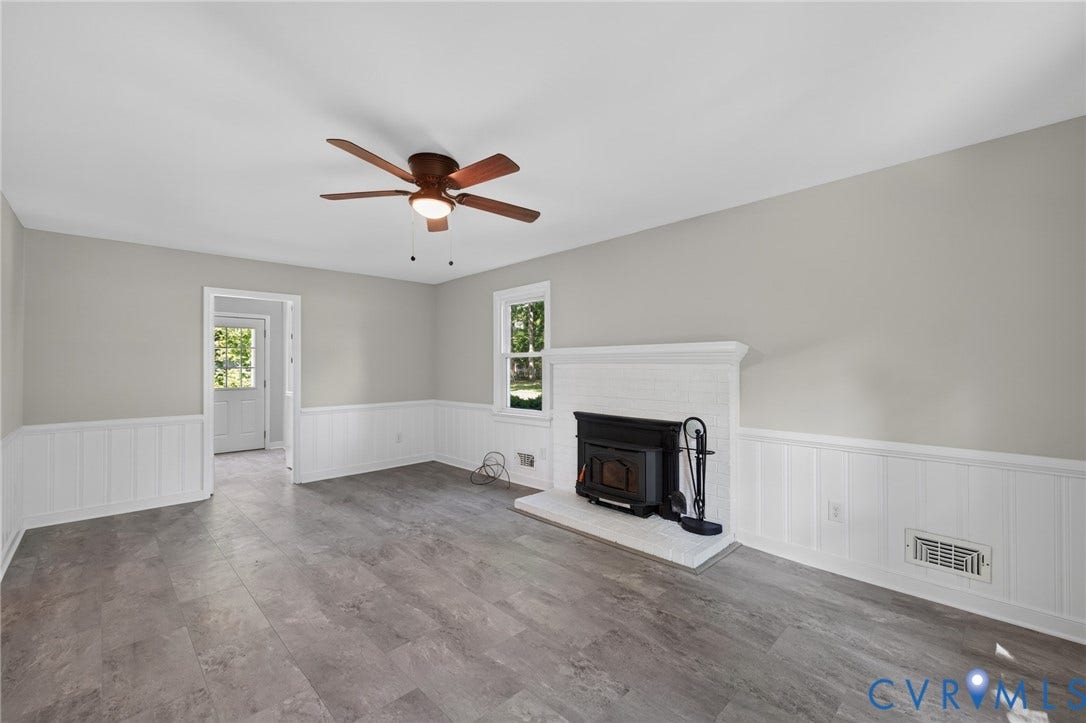 2317 Pleasant Run Drive, Henrico, VA 23238 Wood-finish flooring, white beadboard wainscoting, and a wood stove with a white brick surround and mantel