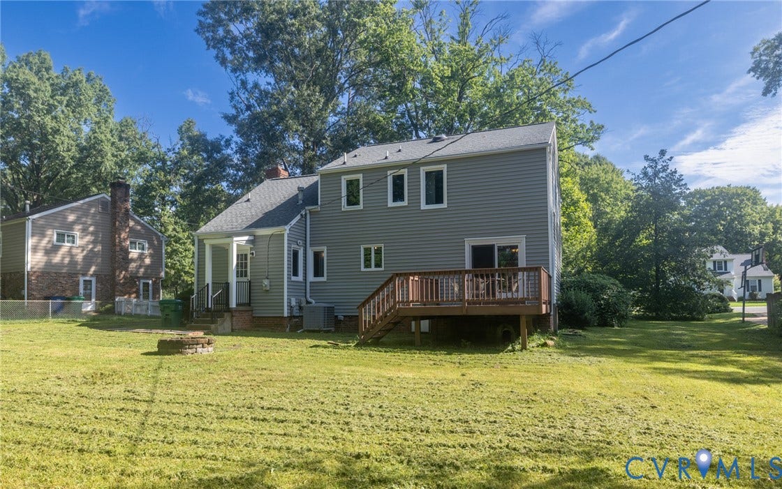 2317 Pleasant Run Drive, Henrico, VA 23238 Expansive grassy yard featuring a wood-finish deck with railings, a stone fire pit, and mature trees