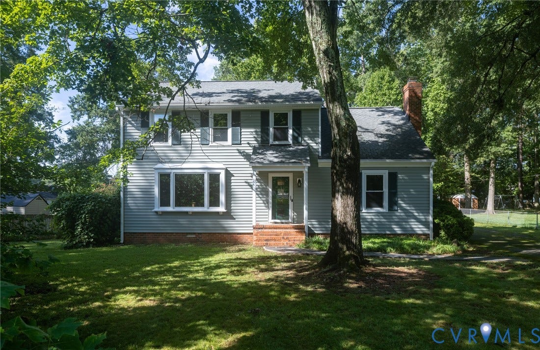 2317 Pleasant Run Drive, Henrico, VA 23238 Two-story residence featuring light gray siding with dark shutters, a front entry with a brick stoop, multiple bay windows, and a prominent brick chimney