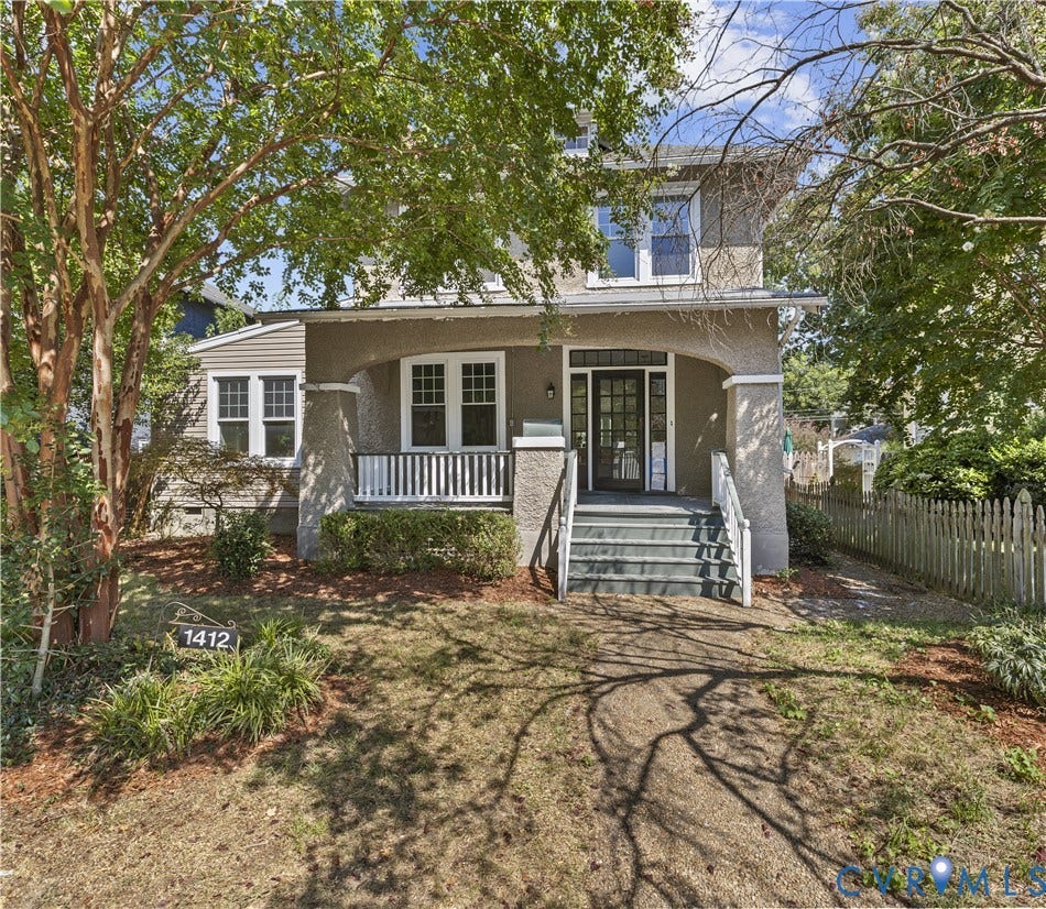 Stucco exterior with a covered front porch, white railing, and exterior staircase