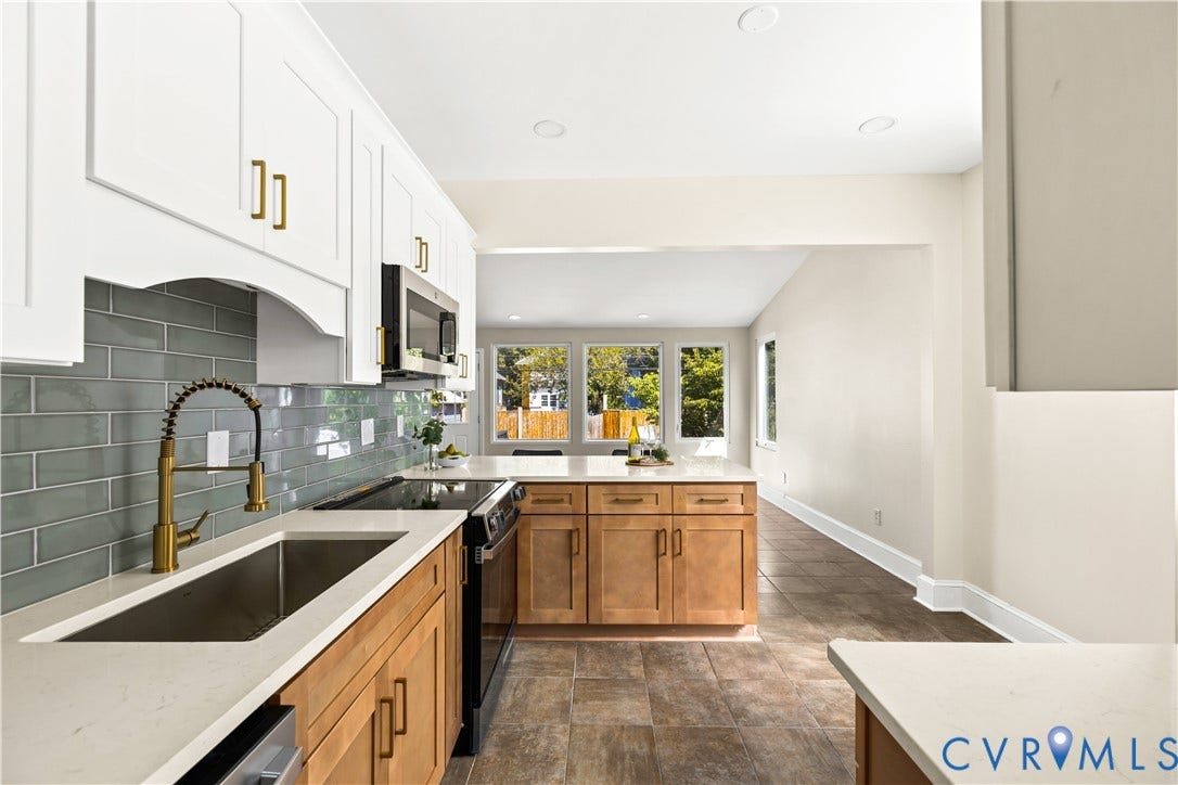 Modern kitchen featuring white upper cabinetry, natural wood-finish lower cabinetry, light-toned countertops, a subway tile backsplash, and stainless steel appliances