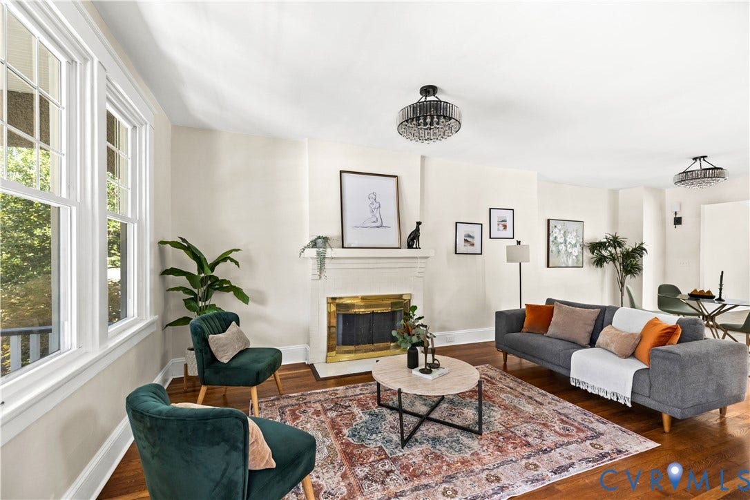 Hardwood flooring, white window frames, recessed fireplace with brass surround, white mantel, and two ceiling-mounted light fixtures