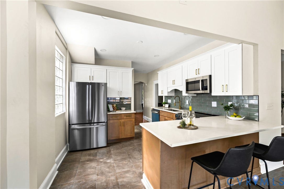Kitchen featuring white cabinetry, stainless steel appliances, a center island with a light-toned countertop, and a tiled backsplash