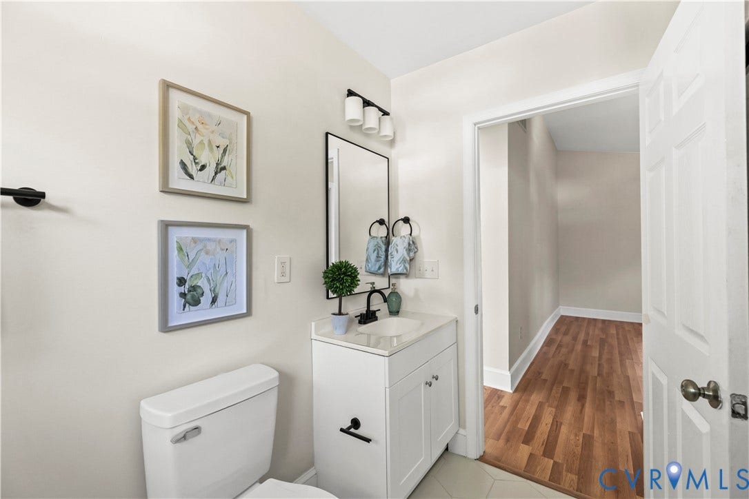 White vanity with integrated sink, black faucet, and rectangular mirror
