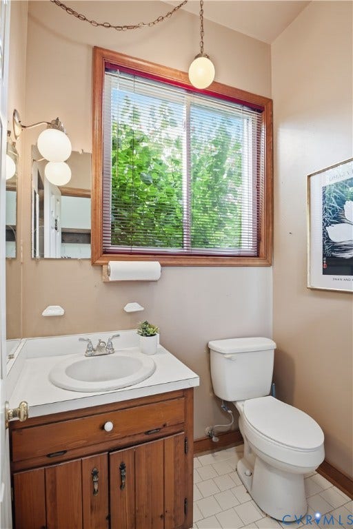 3231 Ludgate Road, Chester, VA 23831 Wood-finish vanity with a white countertop and integrated sink, accompanied by a white toilet