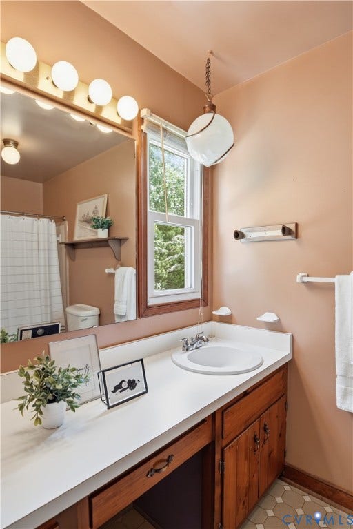 3231 Ludgate Road, Chester, VA 23831 Single vanity with an integrated sink, wood-finish cabinetry, and hexagon-patterned floor tiles