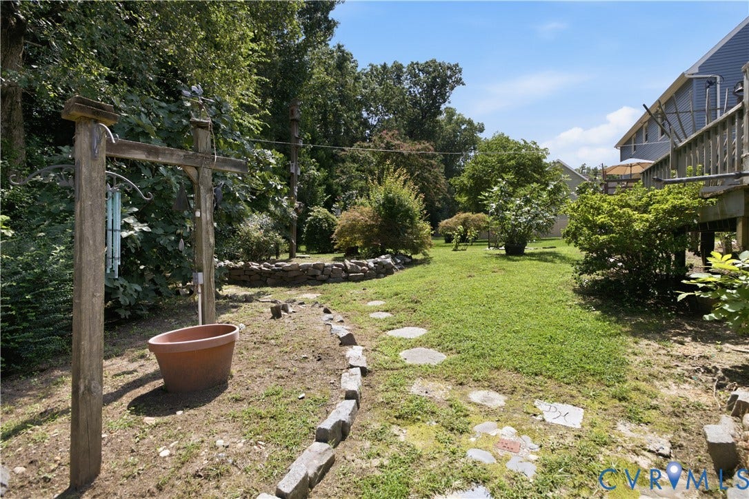 3231 Ludgate Road, Chester, VA 23831 Expansive backyard featuring a manicured lawn, established landscaping, stepping stone pathway, and a wood deck