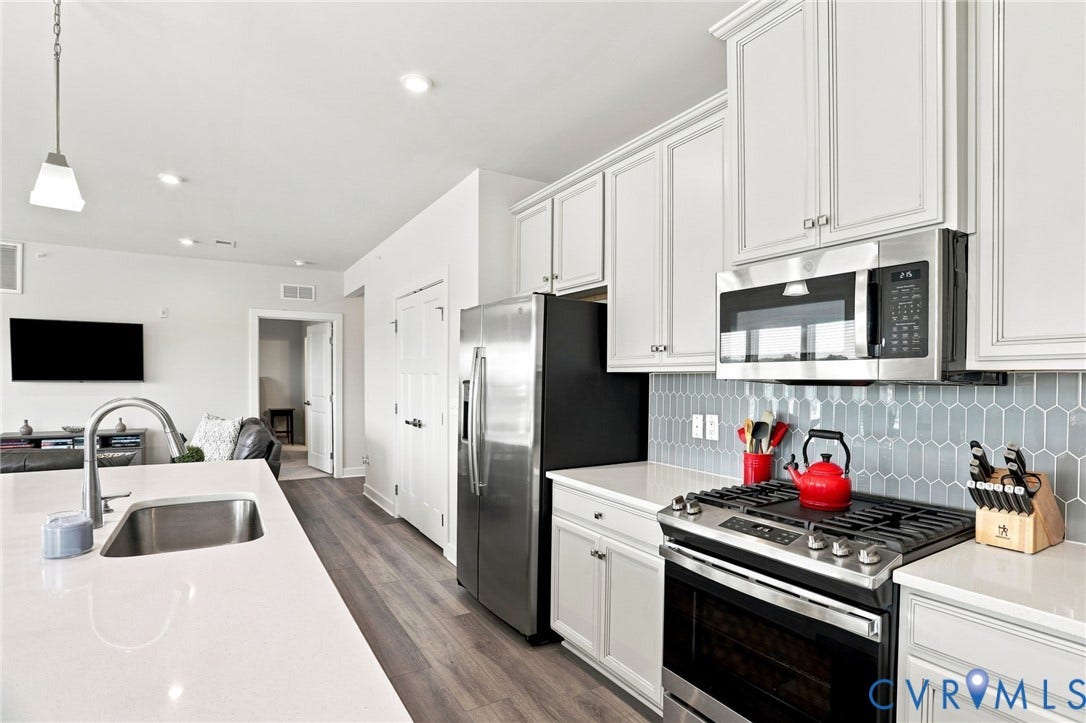 3900 Maze Runner Drive, #403, Midlothian, VA 23112 White shaker-style cabinetry, stainless steel appliances, light-toned countertops, gray picket tile backsplash, and wood-finish flooring