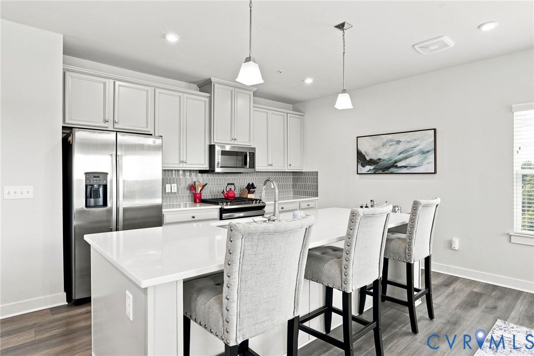 3900 Maze Runner Drive, #403, Midlothian, VA 23112 Kitchen featuring white cabinetry, stainless steel appliances, a tile backsplash, a large island with a sink, and wood-finish flooring