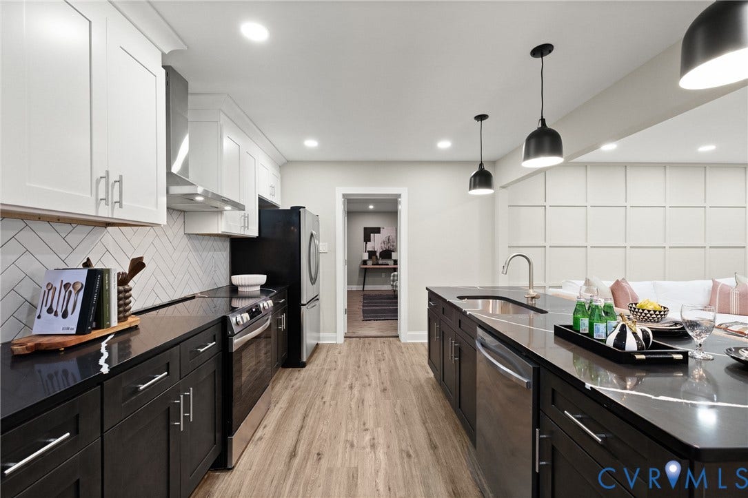 1500 Leicester Road, Cedarhurst - Westover Hills, Richmond, VA 23225 Two-tone cabinetry with white upper and dark lower units, stainless steel appliances, herringbone tile backsplash, wood-finish flooring, and a large kitchen island with pendant lighting