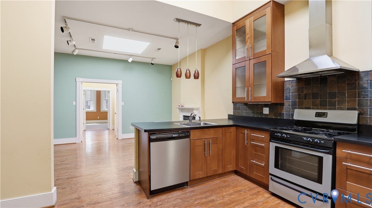 111 N 17th Street, Richmond, VA 23219 Kitchen with wood-finish flooring, stainless steel appliances, dark countertops, and wood cabinetry with glass-front uppers
