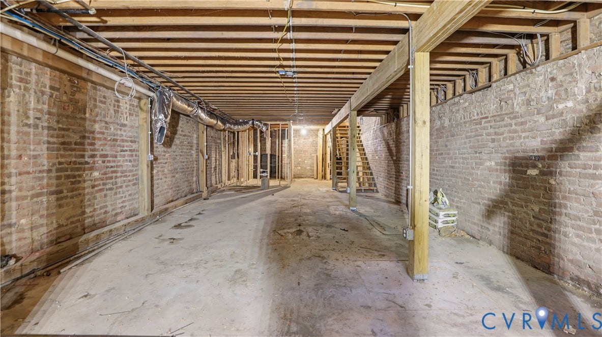 111 N 17th Street, Richmond, VA 23219 Unfinished basement featuring exposed brick walls, wood beam ceiling, concrete flooring, and visible structural framing
