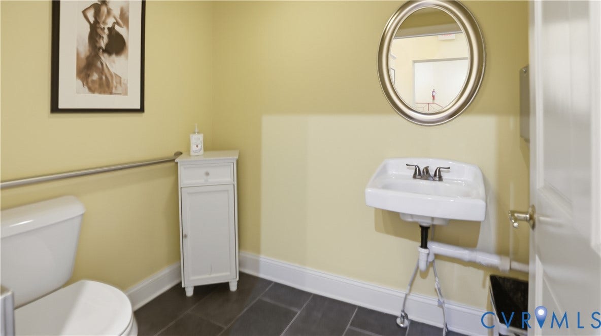 111 N 17th Street, Richmond, VA 23219 Wall-mounted porcelain sink with chrome faucet, complemented by a large oval mirror