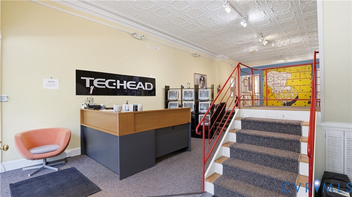 111 N 17th Street, Richmond, VA 23219 Carpeted staircase with red metal railing, a built-in reception desk, and a textured ceiling