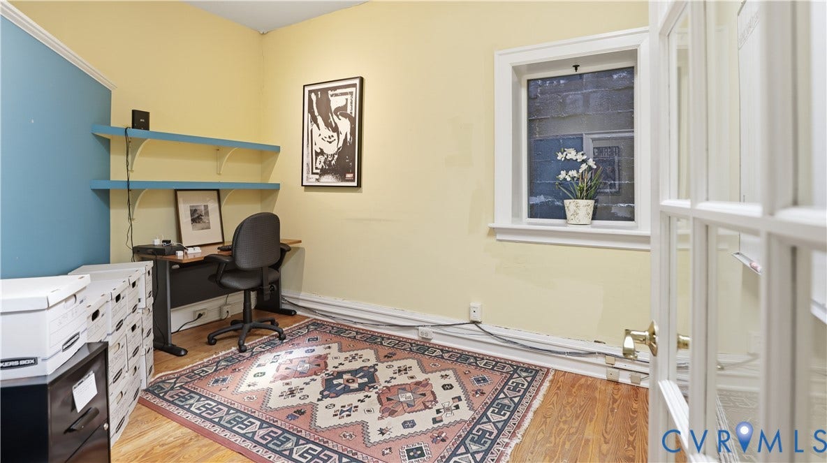 111 N 17th Street, Richmond, VA 23219 Wood-finish flooring with a contrasting accent wall, built-in shelving, and a panel-glass door