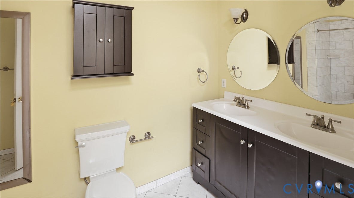111 N 17th Street, Richmond, VA 23219 Dual vanity with integrated sinks, dark wood-finish cabinetry, and circular mirrors
