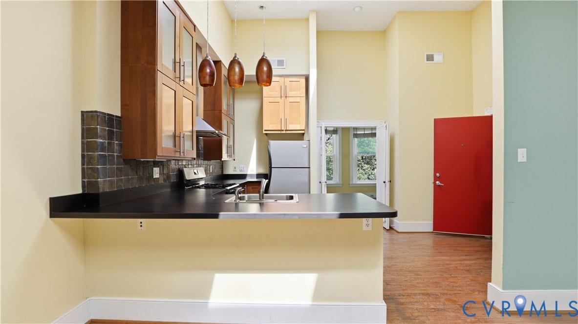 111 N 17th Street, Richmond, VA 23219 Kitchen with wood-finish cabinetry, stainless steel appliances, dark countertops, and a tile backsplash