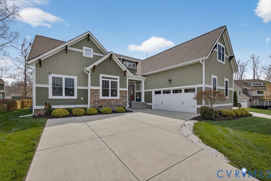 Craftsman-style exterior with stone accents, a red entry door, a multi-car driveway, and an attached garage