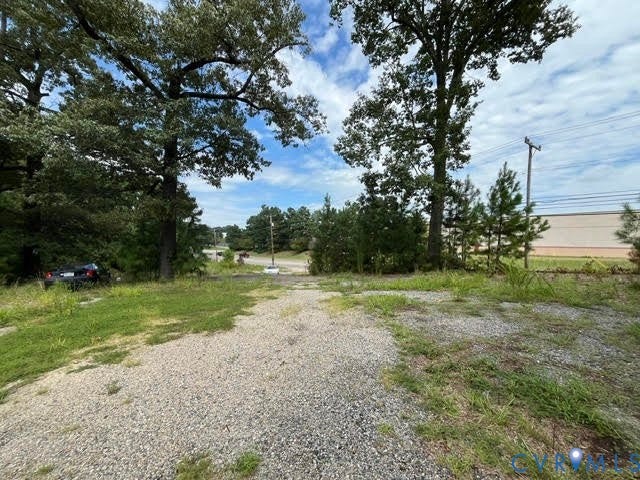 Gravel surface, scattered grass, mature trees