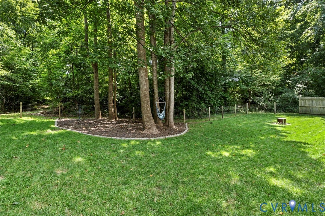 6201 Cameron Bay Terrace, Cameron Bay, Midlothian, VA 23112 Expansive grassy yard with mature trees, a defined mulch bed, and a wooden privacy fence
