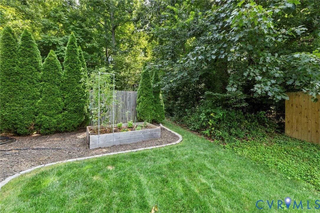 6201 Cameron Bay Terrace, Cameron Bay, Midlothian, VA 23112 Curved lawn area with a raised planter bed, mature evergreen shrubs, and wood privacy fencing
