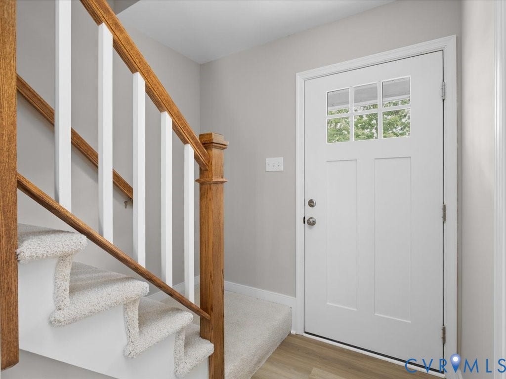 3313 New Found Lane, Chester, VA 23831 Welcoming foyer featuring a white six-panel entry door with glass panes, wood-finish stair railings with white balusters, carpeted staircase, and light wood-finish flooring throughout the entry level