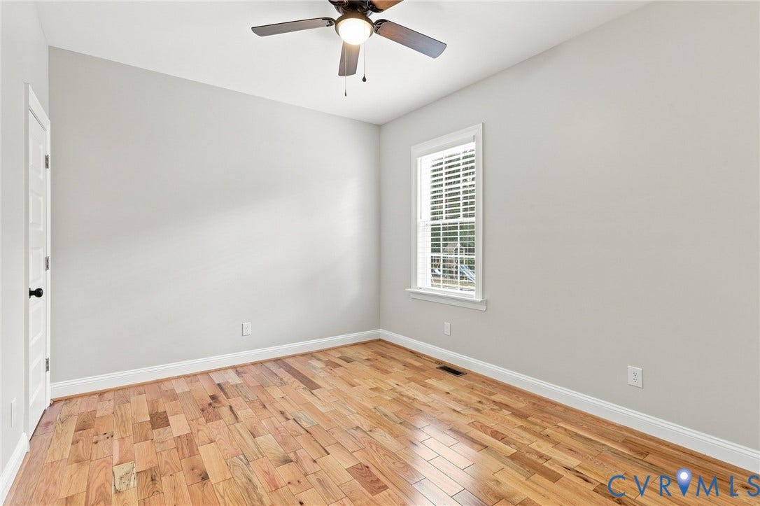 First floor bedroom with hardwood floors, ceiling fan, and great natural lightideal for guests or flexible living space.