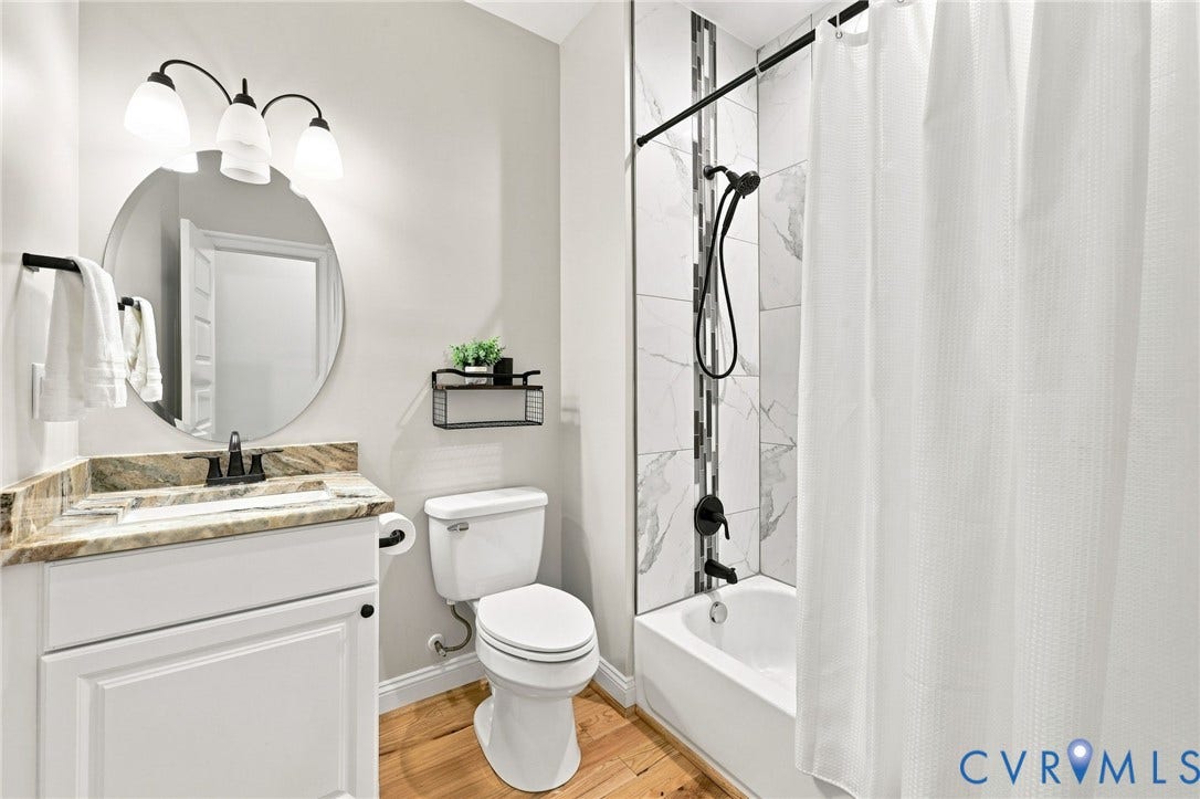 First-floor full bath features a granite-topped vanity and tub/shower combination with updated tile surround and black fixtures.