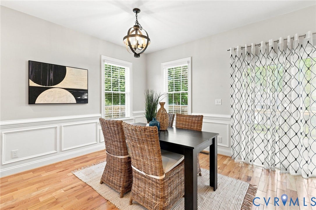 Bright dining area with hardwood floors, decorative wainscoting, and large windows overlooking the backyard.