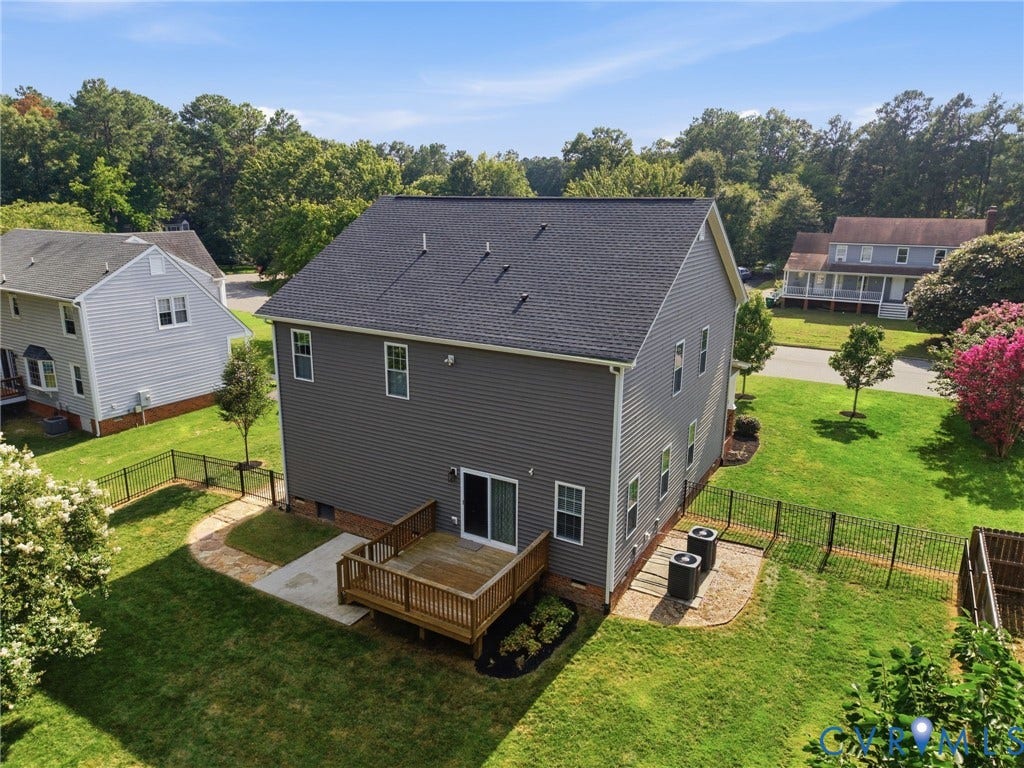 Elevated view showcases the homes rear exterior, deck, fenced yard, and surrounding neighborhood.