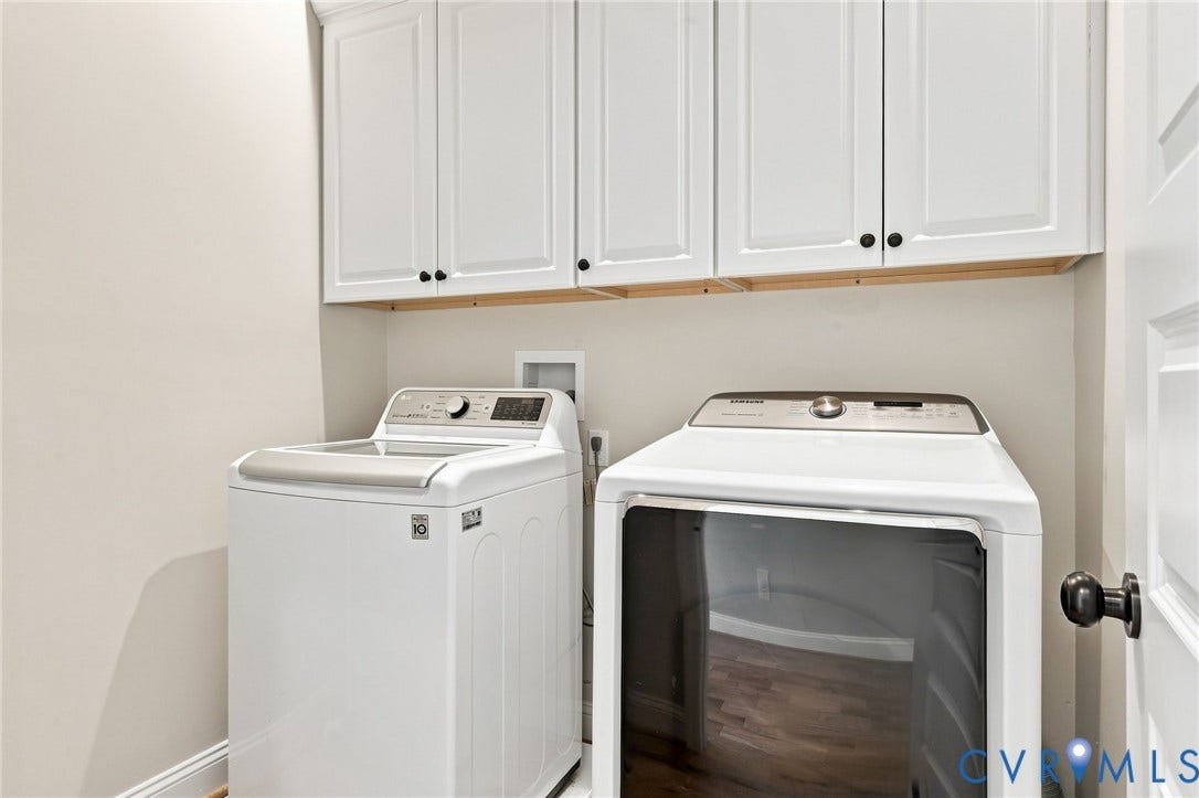 Convenient laundry space with built-in upper cabinetry for added storage.