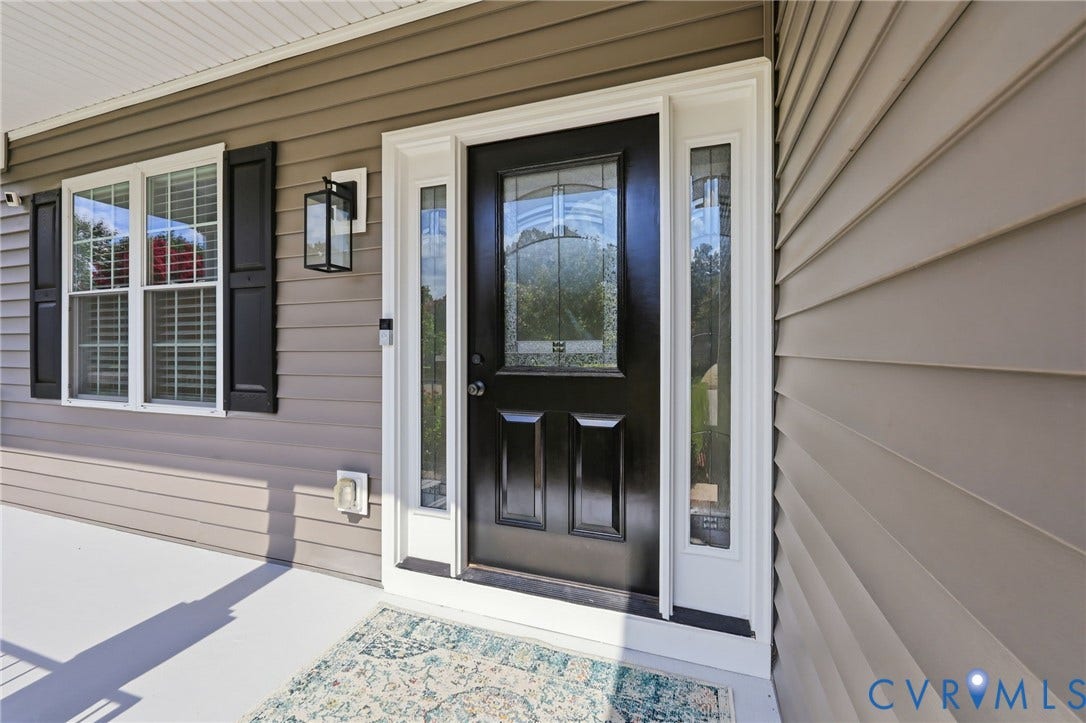 Welcoming front entrance featuring a classic black door with decorative glass and coordinating sidelights