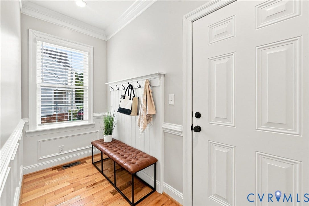 Convenient drop zone off the garage with hardwood floors, decorative molding, and built-in hooks for everyday organization.
