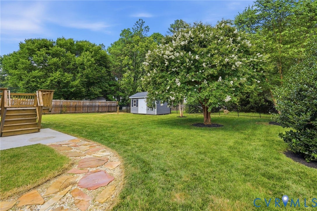 Expansive fenced backyard offers plenty of open lawn space, mature trees, and a detached storage shed.