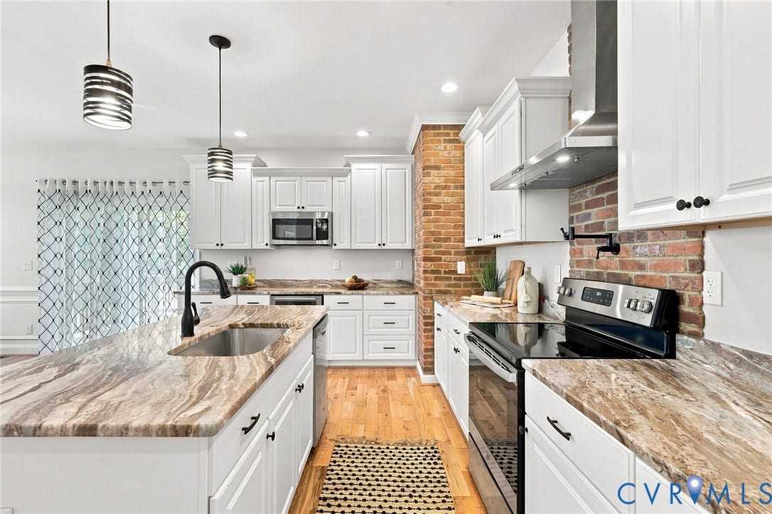 Plenty of cabinet and counter space, stainless steel appliances, hardwood floors, wine fridge, pot filler and a distinctive brick backsplash all add character to this functional kitchen.