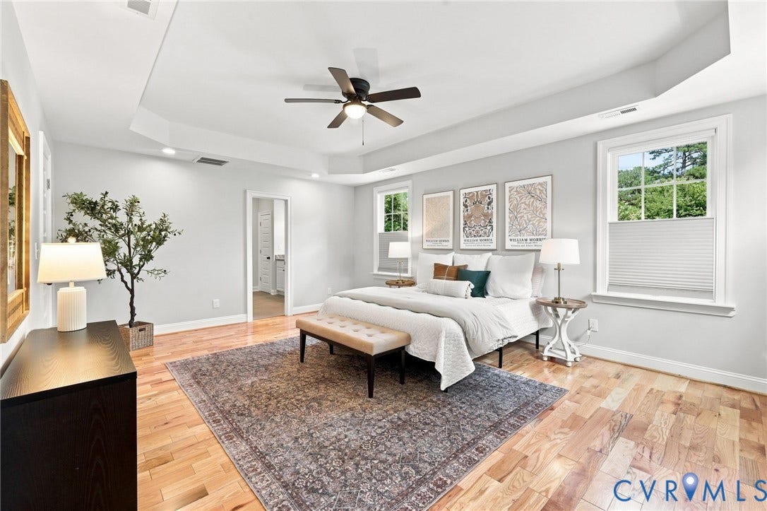 Welcome to the impressive primary suite with hardwood floors, tray ceiling, recessed lighting, and plenty of room for a king-size bed and additional furniture.