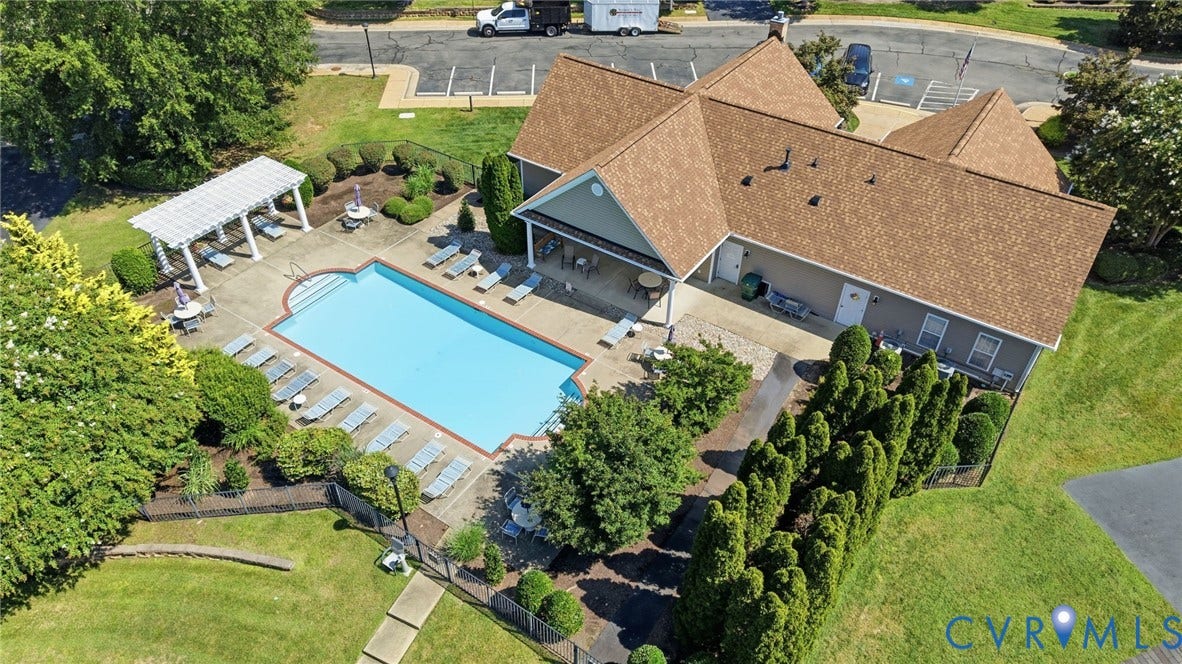 7230 Norwood Pond Court, Midlothian, VA 23112 Rectangular swimming pool with concrete surround, bordered by a white pergola, mature landscaping, and an adjacent building with a covered patio