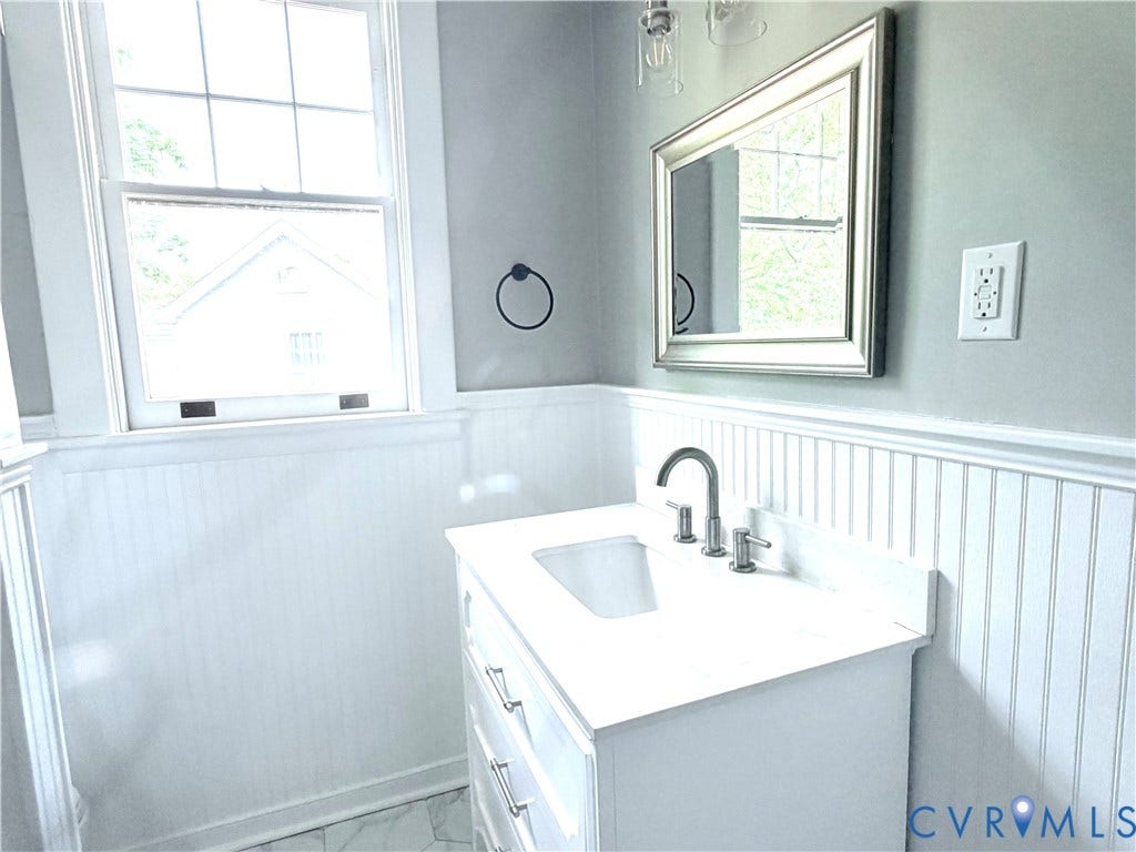 3614 Carolina Avenue, Richmond, VA 23222 White single vanity with an integrated sink, brushed nickel faucet, and a framed wall mirror