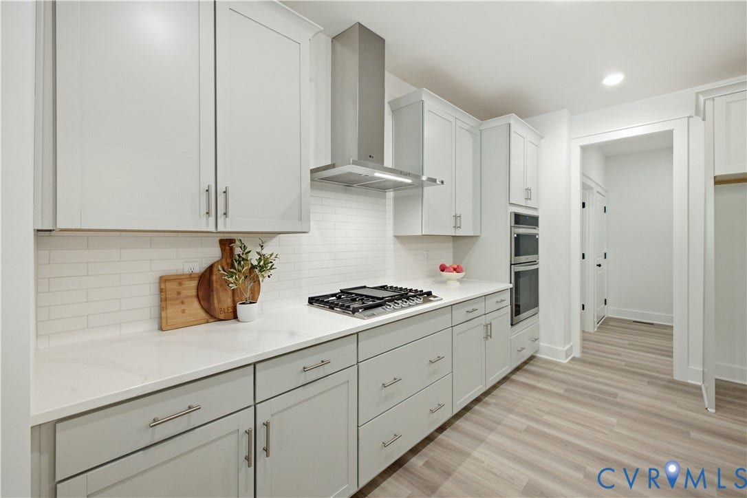 Hood and gas cooktop with drawers below. Wall oven/multipurpose microwave/convection oven. Photos of the for-sale home, staged.
