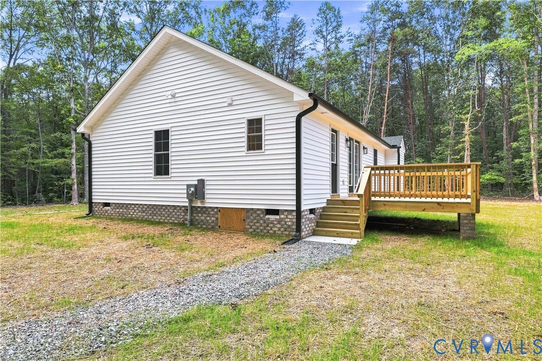 42 Clinton Farm Court, Clinton Farm, Cumberland, VA 23040 White siding exterior with a pitched roofline, elevated wood deck, gravel pathway, and a perimeter of mature trees