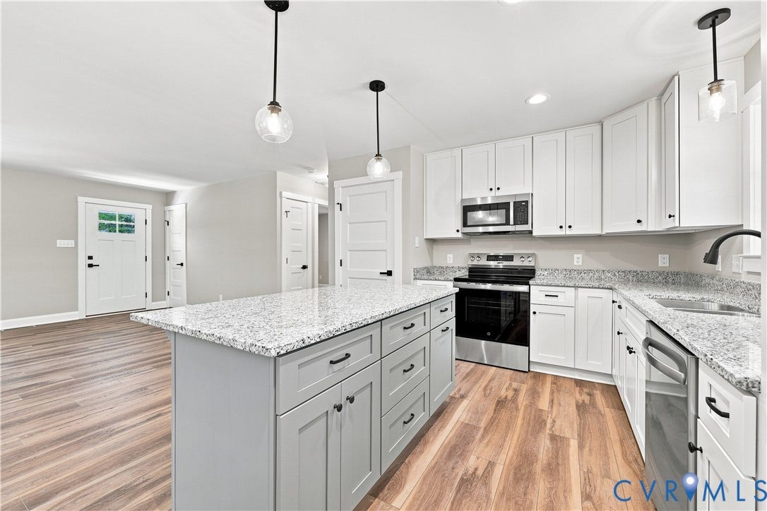 42 Clinton Farm Court, Clinton Farm, Cumberland, VA 23040 Kitchen featuring wood-finish flooring, an island with a light-toned countertop, stainless steel appliances, and white cabinetry