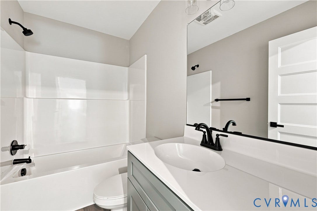 42 Clinton Farm Court, Clinton Farm, Cumberland, VA 23040 Bathroom featuring a white bathtub, shower with matte black fixtures, white vanity countertop with integrated sink, matte black faucet, and a wall-mounted mirror