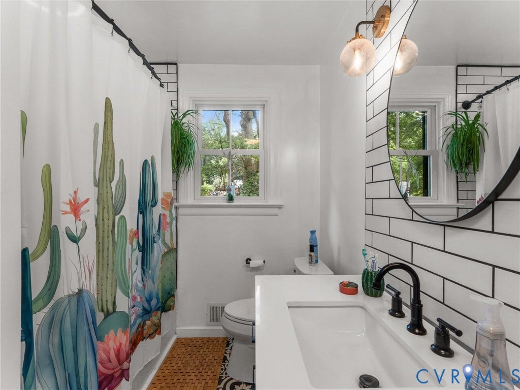 White subway tile wall accenting a vanity with a white countertop and matte black fixtures