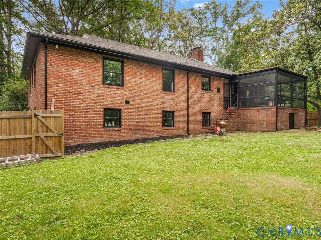 Brick exterior with black-framed windows, screened porch, and a wood privacy fence