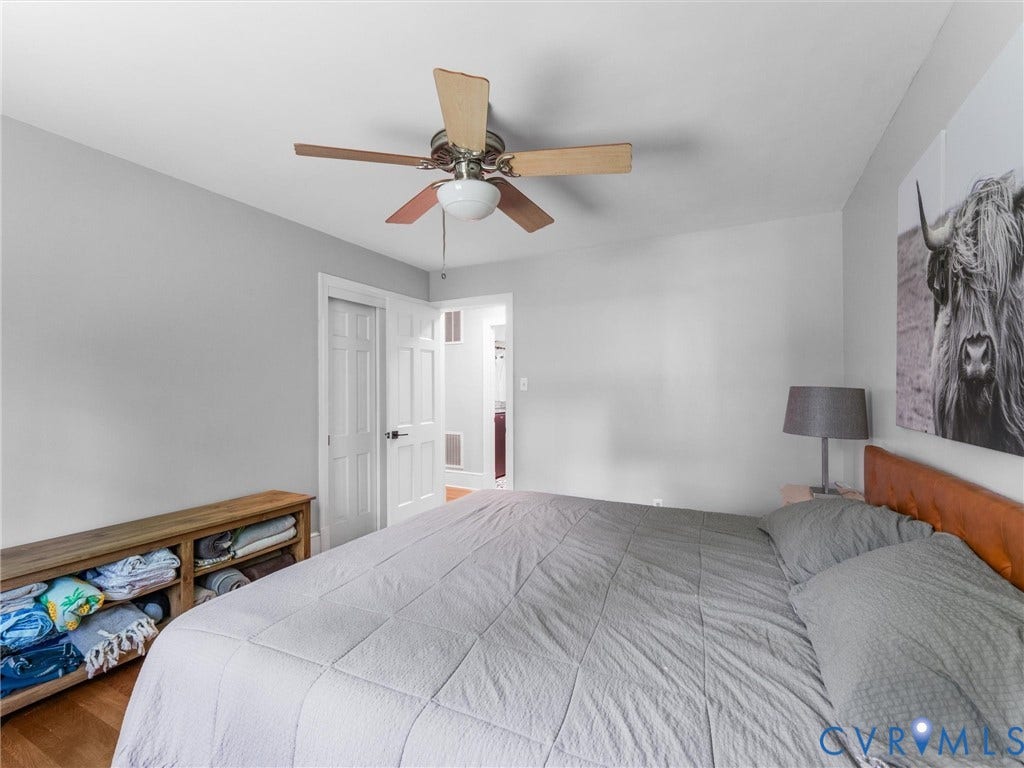 Wood-finish flooring, ceiling fan, and white paneled doors