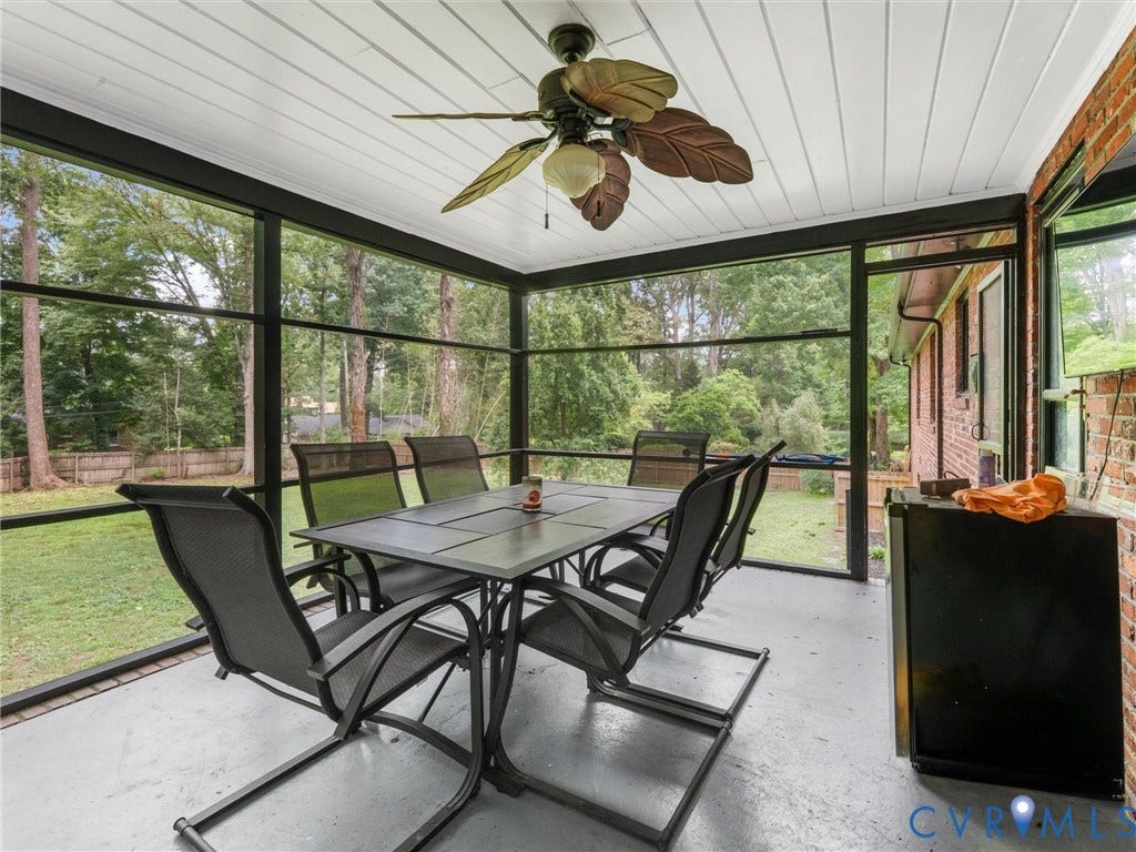 Screened porch with a ceiling fan, white paneled ceiling, and a brick wall accent