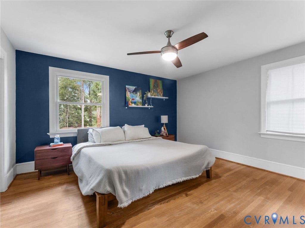 Hardwood flooring, painted accent wall, white trim, ceiling fan, and window